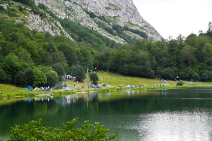 Šatori i kampovanje Mnoštvo šatora i kampera uz jezero na planini. Trnovačko jezero, Maglić.