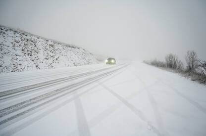 Vožnja vozila po snježnoj i skliskoj cesti. Automobili na asfaltnoj cesti pokrivenoj snijegom. Vožnja u zimskim uslovima.
