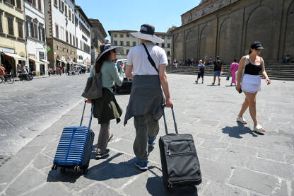 Turisti sa koferima u gradu. Turisti sa koferima u gradu. Ljudi putuju. Firenza, Italija, grupa ljudi na trgu.