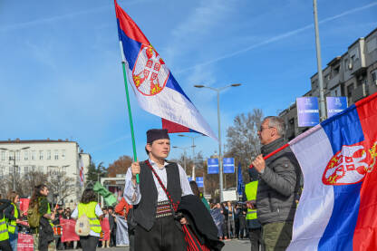 Mladić obučen u srpsku narodnu nošnju, sa zastavom Srbije. Studenti na protestima. Studenti blokiraju Autokomandu 27.01.2025. u Beogradu.