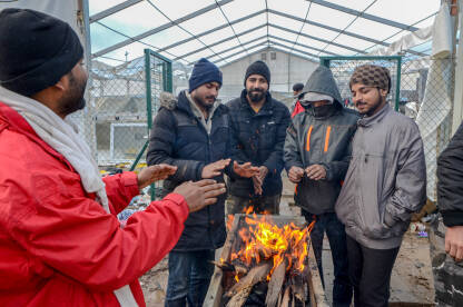 AK1_7084 Grupa migranata se grije uz vatru u kampu. Migracije. Izbjeglice u Bosni i Hercegovini. Balkanska ruta.