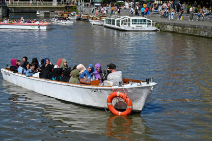 Ghent, Belgija. Turisti u čamcima istražuju grad. Historijske zgrade i rijeka u gradu.