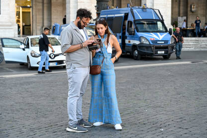 Rim, Italija: Turisti gledaju u mapu na telefonu. Rim, Italija: Turisti gledaju u mapu na telefonu. Ljudi u gradu. Muškarac i djevojka na trgu.