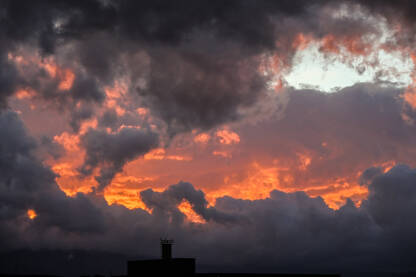 Dramatično nebo i oblaci pri zalasku sunca. Crveni, narandžasti i sivi oblaci na nebu.