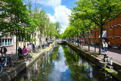 Delft, Nizozemska Delft, Nizozemska: Zgrade i riječni kanal u gradu. Ljudi šetaju gradom.