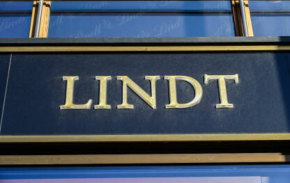Znak LINDT iznad trgovine  čokolade. Logo brenda Lindt. Znak LINDT, poznatog brenda čokolade.