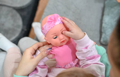 Beba drži lutku. Mama i dijete. Beba drži lutku. Mama i dijete. Majka drži dijete u rukama. Dijete i igračka.
