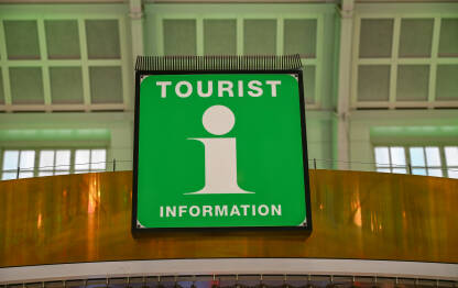 Turistički informativni znak s "i" simbolom. Turistički informativni znak s bijelom ikonom informacija. Osvijetljeni turistički informativni pult zelene boje.