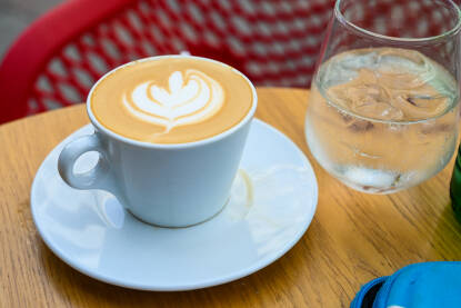 Kafa i mineralna voda na stolu u kafiću. Kafa i mineralna voda na stolu u kafiću. Kafa sa mlijekom servirana u bašti kafića. Macchiato.