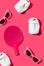 Reket za stolni tenis, prazne limenke i sunčane naočale na magenta pozadini. Reket za stolni tenis, prazne limenke i sunčane naočale na magenta pozadini.
