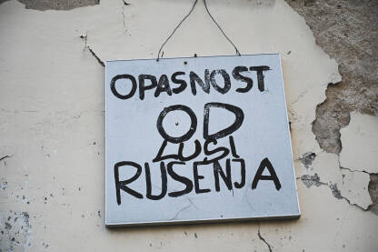Natpis "Opasnost od rušenja" Znak upozorenja: Opasnost od rušenja na zgradi u gradu.