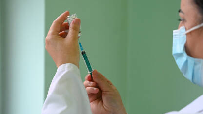 Vakcina Medicinska sestra sa zaštitnom maskom priprema cjepivo. Cijepljenje građana. Liječnik koristi cjepivo i bočicu s lijekom. Antivirusno cjepivo. Covid-19. Cijepljenje protiv koronavirusa. Imunizacacija.