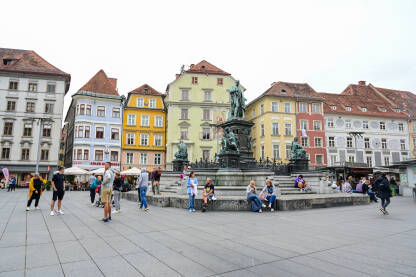 Graz, Austrija: Grupa ljudi na glavnom trgu u centru grada. Graz, Austrija: Grupa ljudi na glavnom trgu u centru grada. Historijske zgrade na glavnom trgu ili Hauptplatzu. Stari grad Graz. Erzherzog-Johann-Brunnen fontana.