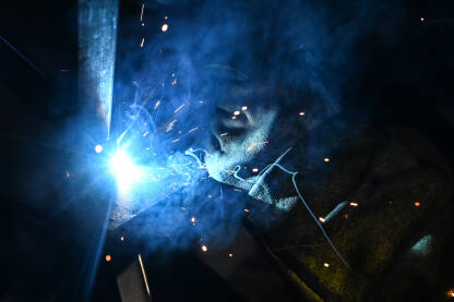 Varilac na poslu, krupni plan. Varioc na poslu, krupni plan. Zavarivanje metala u fabrici. Industrijski radnik.