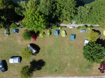 Kamp sa šatorima i kamperima, snimak dronom. Ljetni kamp sa šatorima, vozilima i kamperima. Kamp pored rijeke ljeti.
