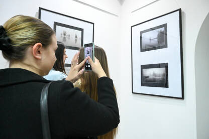Posjetioci posmatraju fotografije u galeriji. Ljudi na izložbi. Posjetioci posmatraju i fotografišu fotografije u galeriji.