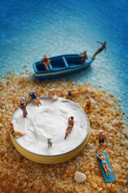 Ilustracija male pješčane plaže sa figuricama ljudi u kremi za sunčanje.