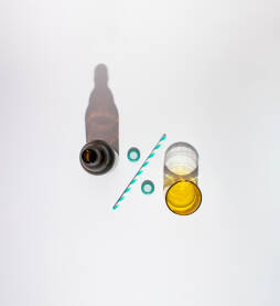 Boca za pivo i staklena čaša Boca za pivo i staklena čaša s papirnom slamkom za piće i dva čepa u obliku znaka za postotak.