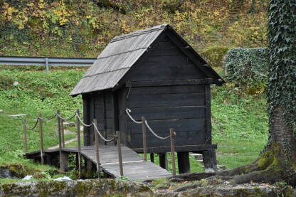 Drveni mlin, Jajce Jedan od mlinčića u Jajcu pored drveta i drvenog mosta sa metalnom ogradom u pozadini.