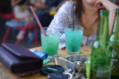 Kokteli u kafiću U kafiću na stolu posluženi plavi kokteli sa slamčicama i pivo. Druženje uz alkohol i cigarete.