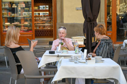 Tri žene piju piće u restoranu Turisti piju piće na terasi restorana. Ljudi sjede u kafiću.