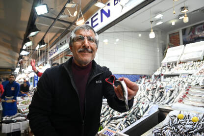 Trgovac na pijaci pokazuje svježu ribu. Ribar prodaje ribu inćune. Prodavač pokazuje škrge ribe da dokaže svježinu ribe.