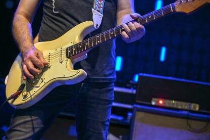 Muzičar svira gitaru na bini na koncertu. Gitarist svira gitaru na festivalu.