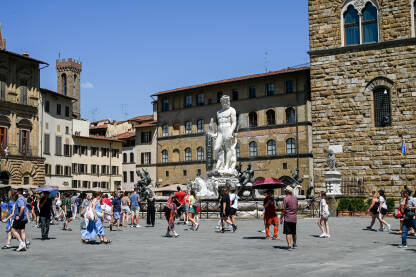 Firenca, Italija: Turisti na trgu. Neptunova fontana. Firenze, Italija: Turisti istražuju grad. Neptunova fontana na Piazza della Signoria. Ljudi šetaju trgom. Zgrade u centru grada.