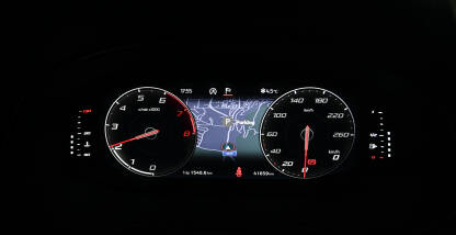 Moderna kontrolna tabla u autu noću. Moderna kontrolna tabla u autu noću. Osvjetljene kazaljke broja obrtaja i brzine na instrument tabli u automobilu. Mapa rute na displeju.