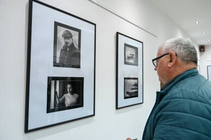 Posjetioci posmatraju fotografije u galeriji. Ljudi na izložbi. Posjetioci posmatraju i fotografišu fotografije u galeriji.
