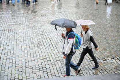 Ljudi na trgu s kišobranom u ruci dok pada kiša. Brisel, Belgija: Ljudi na glavnom trgu u centru grada s kišobranom u ruci dok pada kiša. Turisti hodaju.