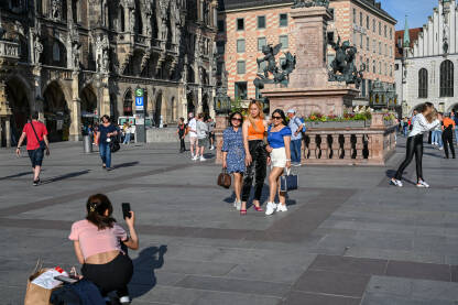 Minhen, Njemačka: Djevojke se fotografišu na trgu. Minhen, Njemačka: Ljudi se fotografišu mobilnim telefonom na trgu. Turisti u gradu.
