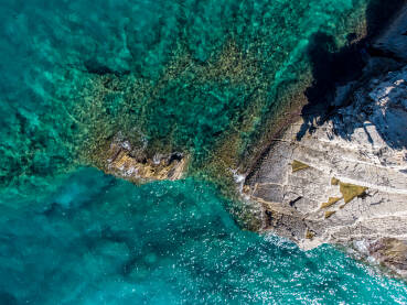 More i stijene na plaži More i stijene na plaži, snimci dronom. Prekrasna prirodna stjenovita plaža tokom ljeta. Valovi se razbijaju na divljoj plaži pri zalasku sunca. Obala. Prozirna morska voda.