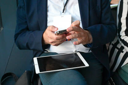 Muškarac koristi mobilni telefon i tablet Čovjek koristi mobilni telefon i tablet na sastanku. Muškarac u odijelu drži pametni telefon u rukama.