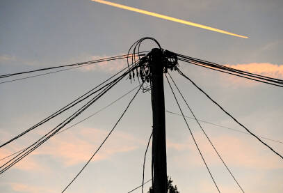 Mnoštvo električnih kablova na banderi tokom zalaska sunca. Mnoštvo električnih kablova na banderi tokom zalaska sunca sa avionom u pozadini. Električna energija. Prijenos električne energije.