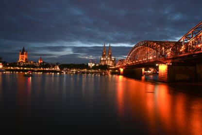 Köln, Njemačka Köln, Njemačka. Poznati most Hohenzollern. Zgrade u staroj gradskoj jezgri. Tornjevi katedrale i gradske vijećnice noću.