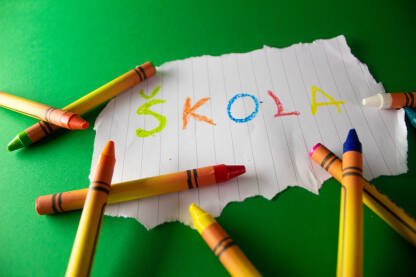 Skola Voštane bojice na zelenoj podlozi koja simbolizuje školsku tablu. Koncept sa papirićem, na kojem piše Škola i simbolizuje početak školske godine.