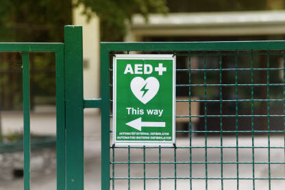 AUTOMATSKI EKSTERNI DEFIBRILATOR-AED Tabla sa znakom smjera za eksterni defiblirator na ogradi.
