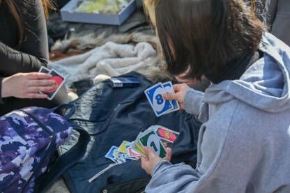 Mladi ljudi se zabavljaju igrajući karte. Dvije djevojke drže karte Uno.