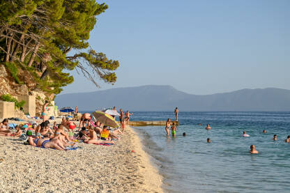 Turisti se kupaju na moru i sunčaju na plaži na Jadranskom moru. Turisti se kupaju na moru i sunčaju na plaži na Jadranskom moru. Turizam u Hrvatskoj ljeti.
