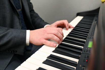 Muškarac svira na klaviru Čovjek svira klavir. Ruke muzičara. Električni piano. Sviranje muzičkog instrumenta u crkvi. Pijanist za klavijaturom.