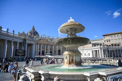 Vatikan: Turisti ispred fontane na trgu svetog Petra. Grupa ljudi na trgu u Vatikanu ispred bazilike sv. Petra.