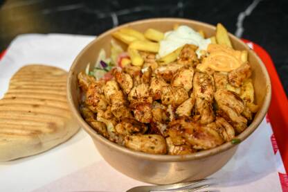 Doner kebab u restoranu. Hrana. Pečeno meso, krompir i povrće servirani u činiji u restoranu. Doner kebab. Hrana.