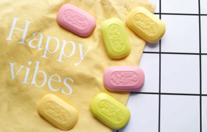 Razne boje čvrstih sapuna na žutom platnu i happy vibes parola.