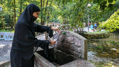 Žena sa nikabom sipa vodu Žena sa nikabom sipa vodu u flašu iz česme. Vrelo Bosne, popularna turistička destinacija u BiH.