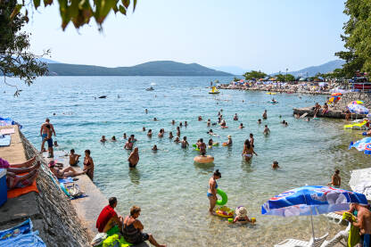 Ljudi u Neumu Neum, Bosna i Hercegovina: Grupa ljudi u moru i na plaži. Mladi se zabavljaju na ljetovanju. Ljudi se kupaju u Jadranskom moru.