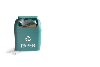 Kanta za reciklažu papira Zelena plastična kanta za znakom za recikliranje papira na bijeloj podlozi.