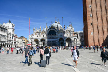 Venecija, Italija: Ljudi šetaju glavnim trgom. Piazzetta San Marco. Popularna turistička destinacija. Zvonik, Bazilika svetog Marka i Duždeva palača u centru grada.