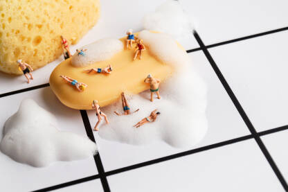 Žuti sapun i spužva na podu sa pjenom i figuricama koje se kupaju.