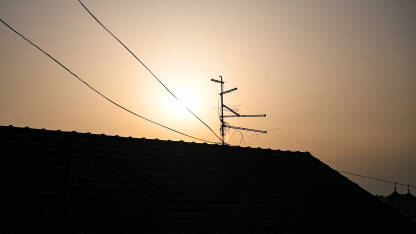 TV antena i kablovi TV antena i kablovi na krovu kuće tokom zalaska sunca.